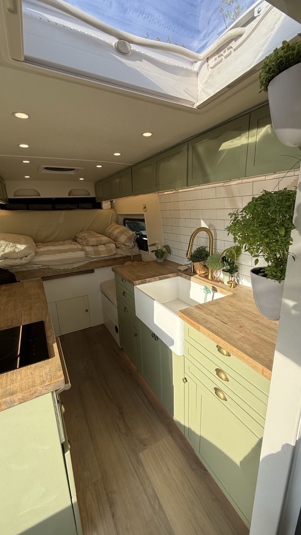 Bright finished van interior with green cabinets, sink and bed